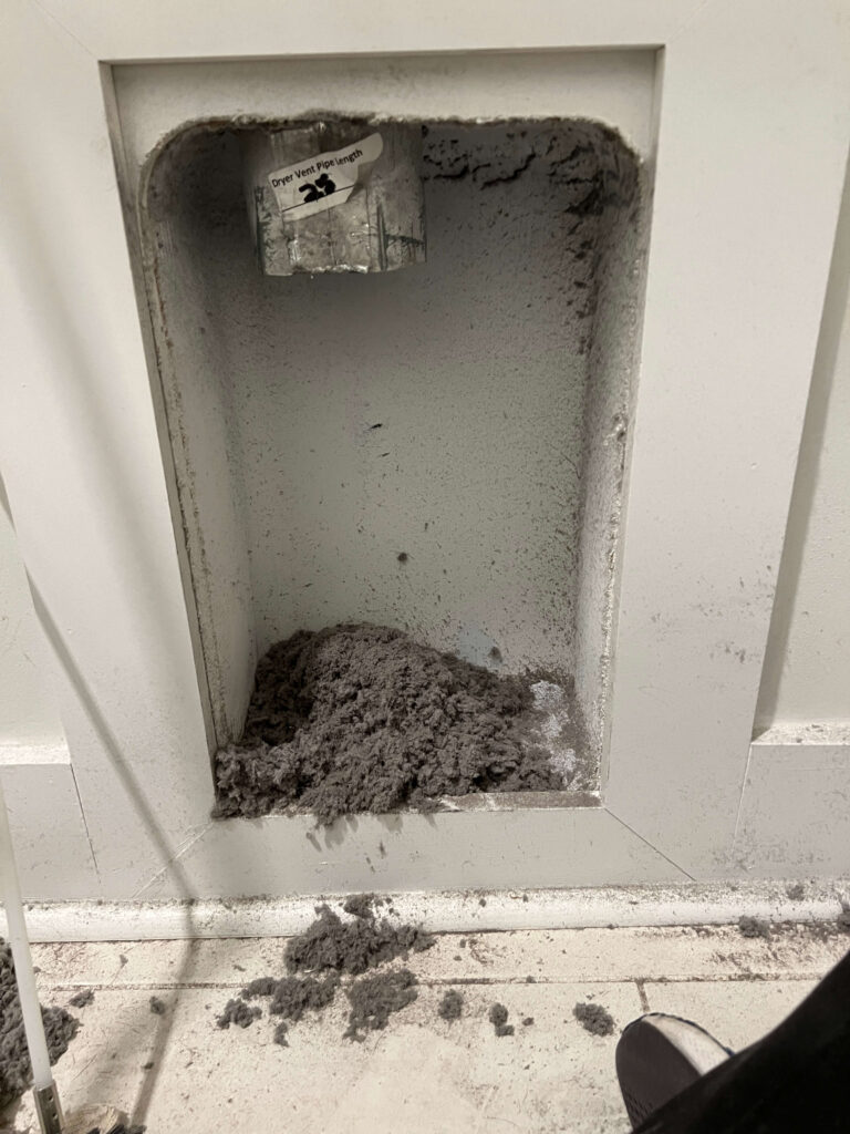 A pile of lint debris cleaned from the dryer vent above.